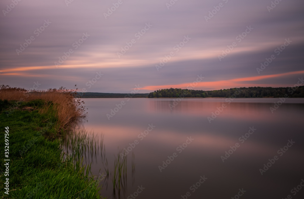 Long exposure sunset view on Ivano-Frankove Yaniv , Yanivskyi Stav Lake and forest. Roztochia Biosphere Reserve, Lviv district, Ukraine. May 2020