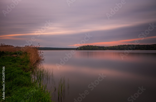 Long exposure sunset view on Ivano-Frankove Yaniv , Yanivskyi Stav Lake and forest. Roztochia Biosphere Reserve, Lviv district, Ukraine. May 2020