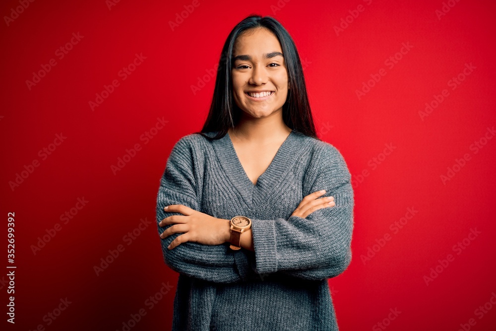 Young beautiful asian woman wearing casual sweater standing over isolated red background happy face smiling with crossed arms looking at the camera. Positive person.