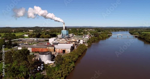 Workshops and industrial sheds around tall chimney exhausting steam in Broadwater sugar mill on shores of Richmond river around Grafton and Ballina in NSW, Australia.
 photo