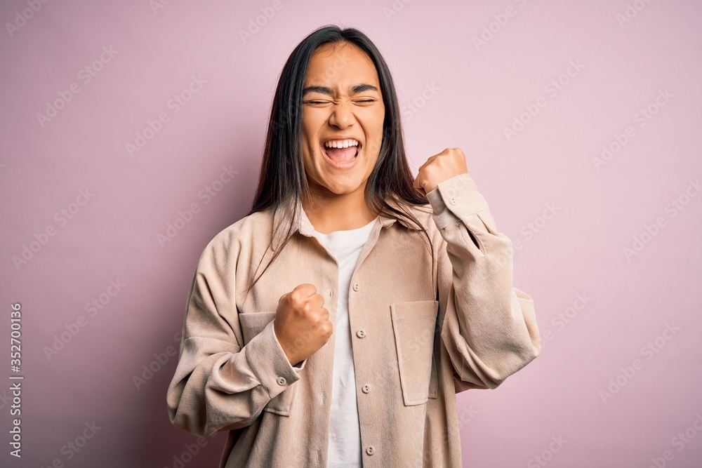 Young beautiful asian woman wearing casual shirt standing over pink background celebrating surprised and amazed for success with arms raised and eyes closed. Winner concept. Young beautiful asian woman wearing casual shirt standing over pink background celebrating surprised and amazed for success with arms raised and eyes closed. Winner concept.