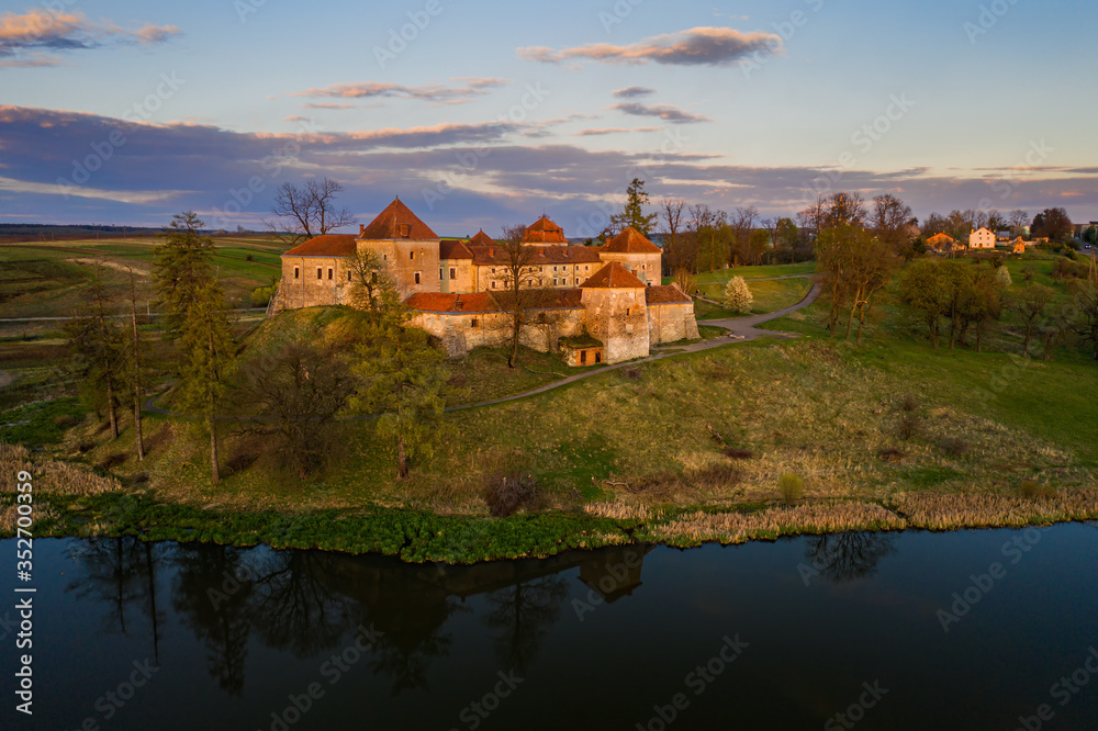 The beautiful medieval castle in the village of Svirzh Swirz in Western Ukraine in late calm evening, aerial view. Mighty fortress is popular tourist destination and place of summer opera festival