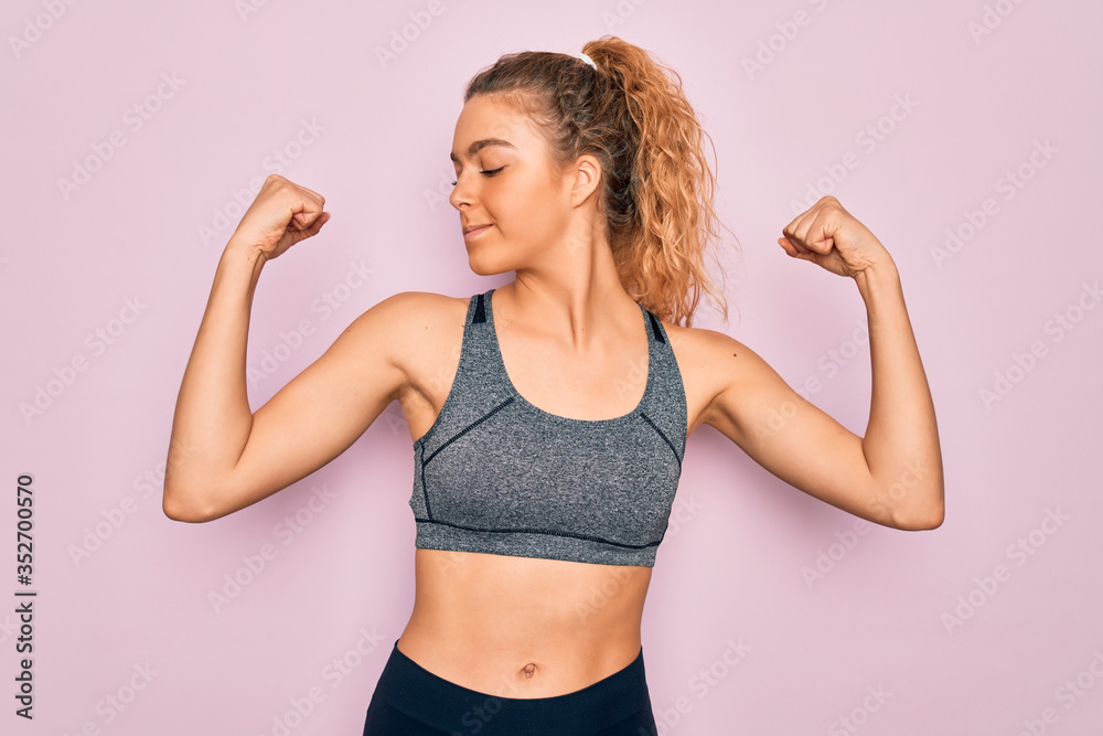 Young beautiful blonde sportswoman with blue eyes doing exercise wearing sportswear showing arms muscles smiling proud. Fitness concept. Young beautiful blonde sportswoman with blue eyes doing exercise wearing sportswear showing arms muscles smiling proud. Fitness concept.