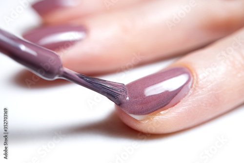 Woman applying nail polish. Beautiful nails. Woman applying polish on nails at home. Pastel nail polish on fingernail. Beauty treatment and hand care concept. manicure procedures yourself at home