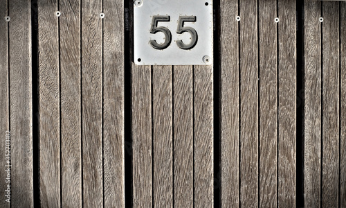 Number fifty-five (55), metal plate on teak background, slight vignette. photo