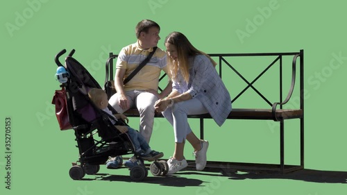 A young family with a little son sitting on a bench. Green screen video