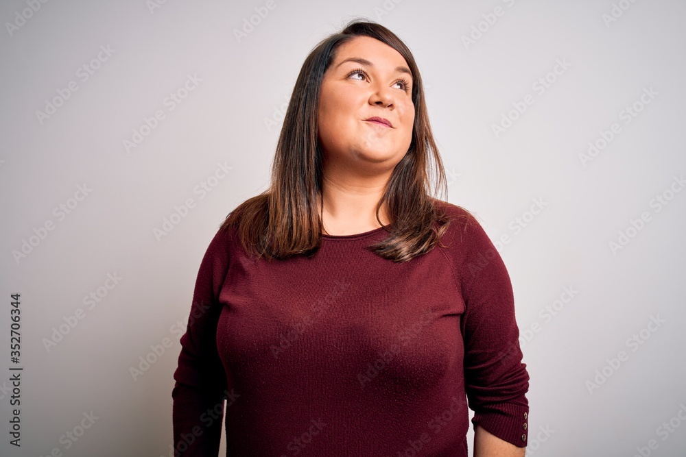 Beautiful brunette plus size woman wearing casual sweater over isolated white background smiling looking to the side and staring away thinking. Beautiful brunette plus size woman wearing casual sweater over isolated white background smiling looking to the side and staring away thinking.