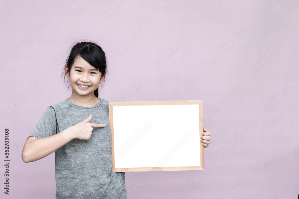 Little asian girl holding whiteboard isolated on gray background. Little asian girl holding whiteboard isolated on gray background.