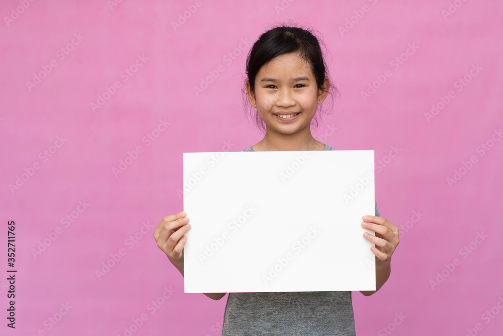 Little asian girl holding white paper isolated on pink background. Little asian girl holding white paper isolated on pink background.