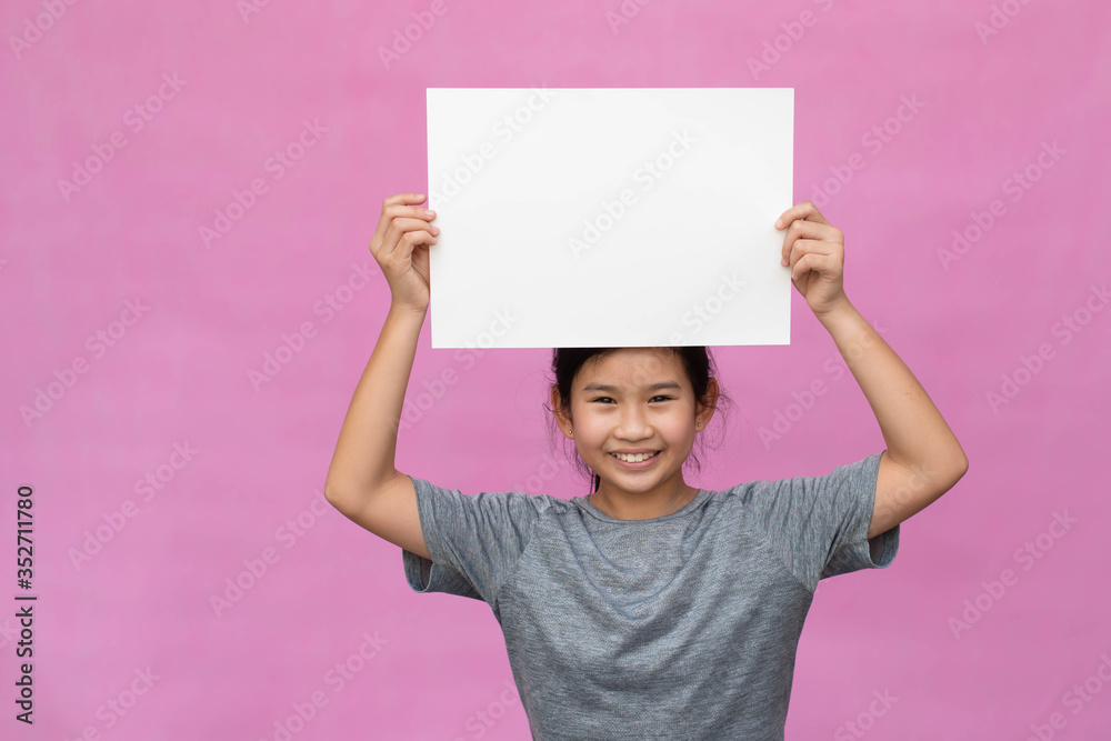 Little asian girl holding white paper isolated on pink background. Little asian girl holding white paper isolated on pink background.