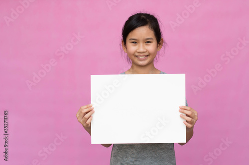 Little asian girl holding white paper isolated on pink background.
