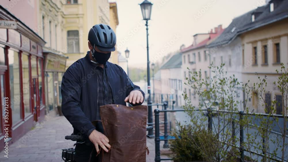 Delivery man courier with face mask and bicycle delivering parcels in town. Delivery man courier with face mask and bicycle delivering parcels in town.