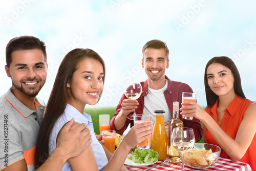 Group of friends having picnic at table in park