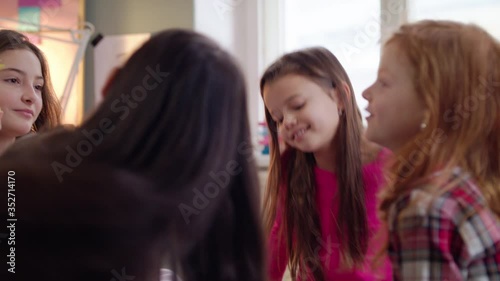 Group of small girls friends playing on bed on slumber party, having fun.