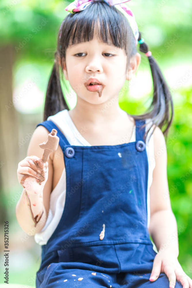 Close up background view Of ASEAN girls eating delicious ice cream, with chocolate flowing on clothes, the concept of self-learning Close up background view Of ASEAN girls eating delicious ice cream, with chocolate flowing on clothes, the concept of self-learning