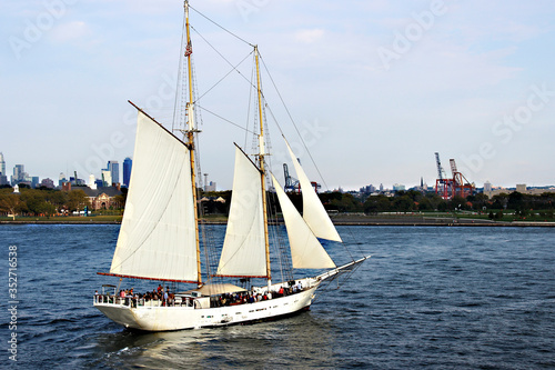 New York, NY, USA. September 20, 2017. Yacht with white sails and passengers on the background of Governors Island near New York.