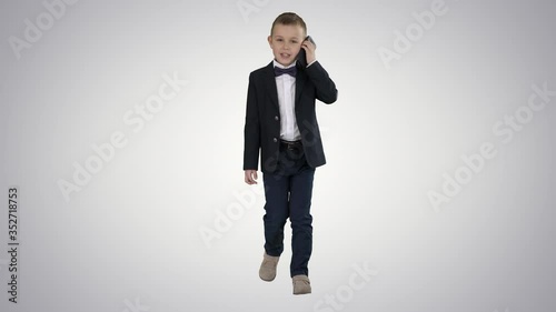 Little boy in a costume making a phone call while walking on gradient background. photo