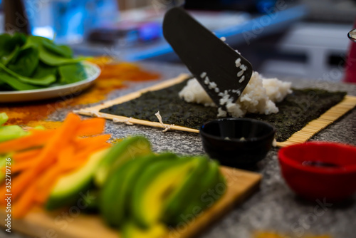 Preparation of vegan sushi. Cooked rice combined with rice vinegar and sugar and vegan ingredients are placed and seaweed is rolled with the help of bamboo mat