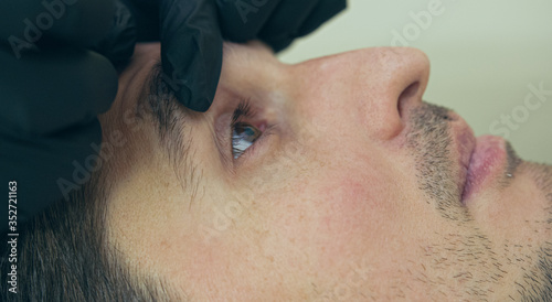 High quality close-up of a man laying on a couch during the esthetician lips treatment. Male permanent make-up service.