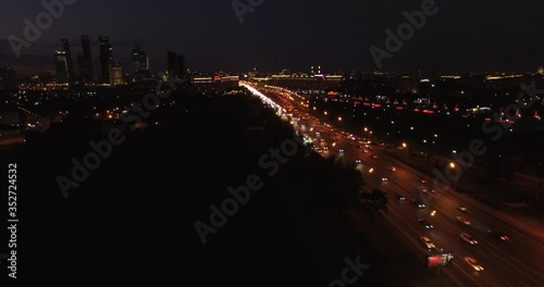 4K early night aerial video of busy road traffic with background view of high-rise buildings and memorial complex in Moscow, Russia