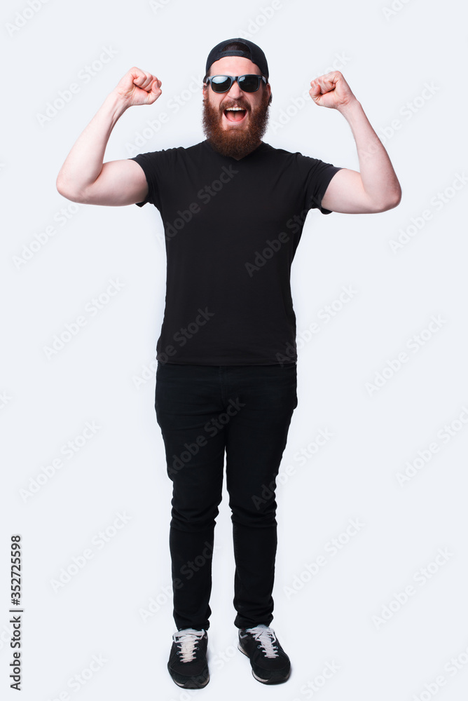 Full length photo amazed bearded man celebrating victory over white Full length photo amazed bearded man celebrating victory over white