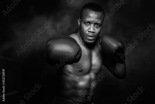 african american boxer punching with glove in dark background © Mongkolchon