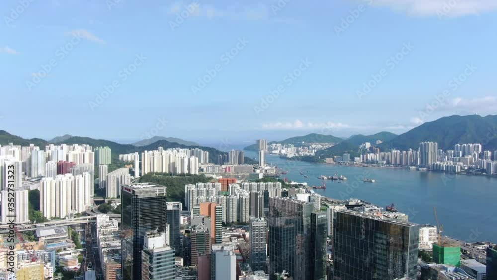 Aerial view of Hong Kong skyline and residential skyscrapers on both sides of the bay, on a clear day.