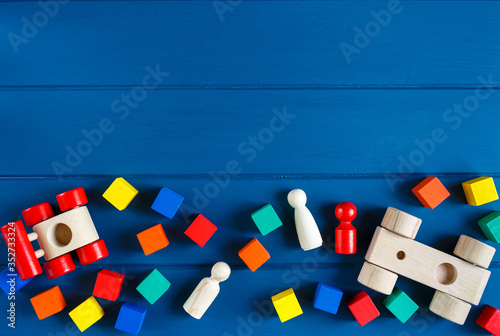 Fototapeta Naklejka Na Ścianę i Meble -  Multicolored wooden toys cubes, pyramid and cars on classic blue background. Set colorful toys for games in kindergarten, preschool kids. Close up, top view, copy space