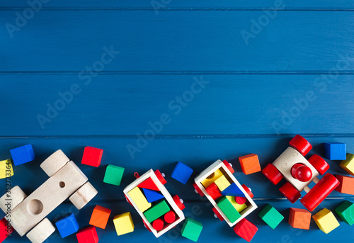 Fototapeta Multicolored wooden toys cubes, pyramid and cars on classic blue background