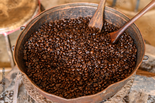 An old metal pot containing dark roast coffee beans after roasting. Roasting brings out the aroma and flavor inside coffee beans.