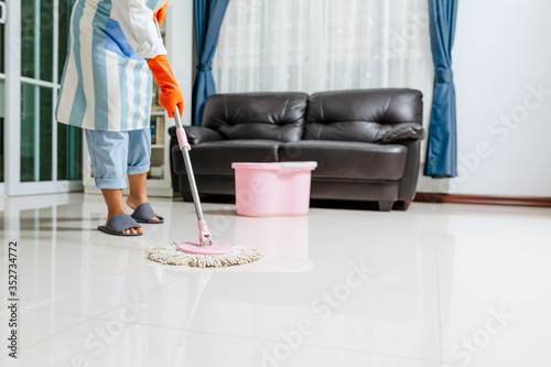 Foto Asian beautiful young woman in protective gloves using a flat wet-mop while cleaning floor in the house, The housekeeper uses a mop to clean the house