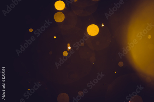 Dark Abstract Gold bokeh sparkle on black background © pandaclub23