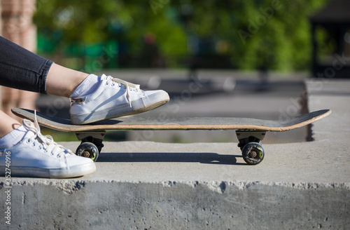 Skateboard and women's feet on the background of city streets. © papa
