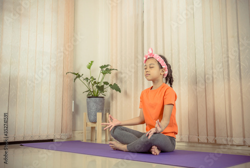 Happy little cute girl practicing yoga at home, Kids' sport concept