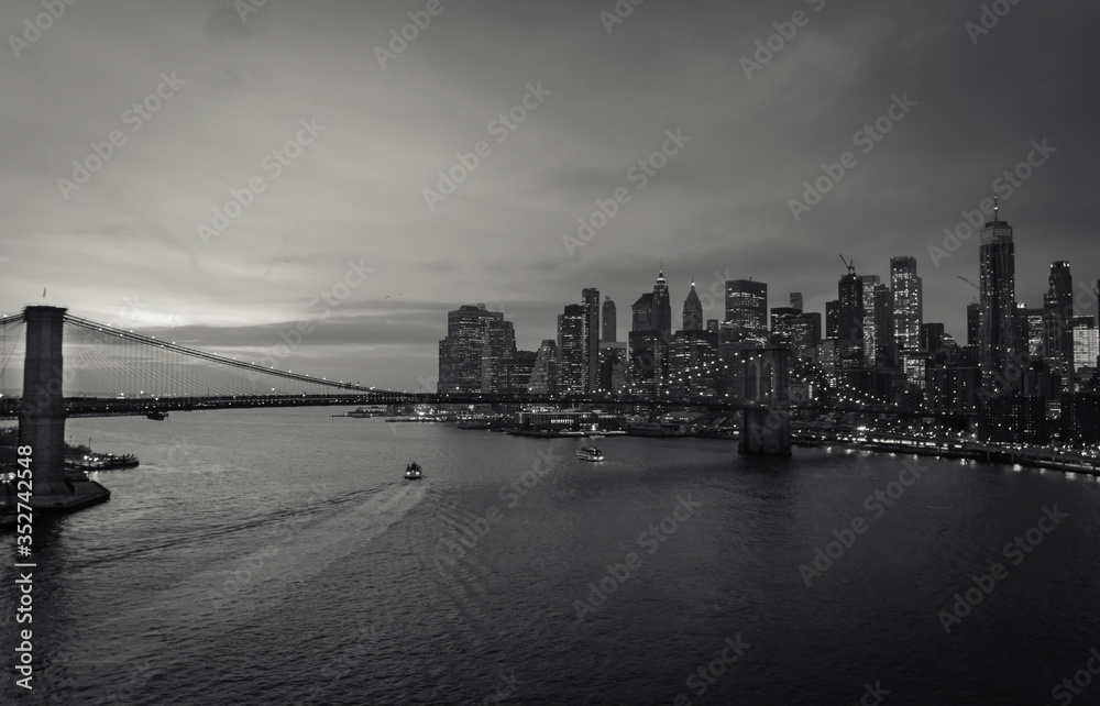 New York City, USA - 26 Dec 2019: (Black and White) Evening Scene at the East River with Manhattan Skyline Lights and Brooklyn Bridge