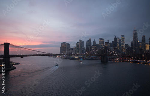 New York City  USA - 26 Dec 2019  Dramatic  colorful Sunset at the East River with Manhattan Skyline Lights and Brooklyn Bridge