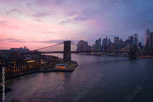 New York City, USA - 26 Dec 2019: Dramatic, colorful Sunset at the East River with Manhattan Skyline Lights and Brooklyn Bridge