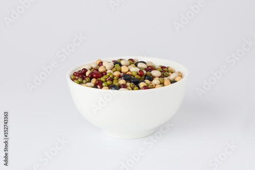 Five natural mixed raw legumes, pulses in white bowl.