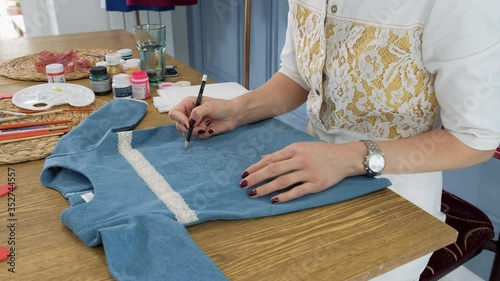 Designer painting on denim cloth. Making personal collection dresses for girls