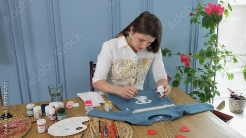 Designer painting on denim cloth. Making personal collection dresses for girls