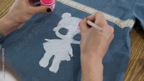 Designer painting on denim cloth. Making personal collection dresses for girls