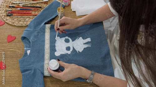 Designer painting on denim cloth. Making personal collection dresses for girls