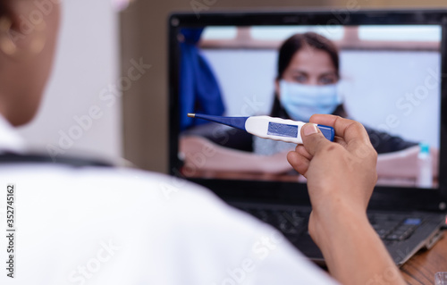 Doctor explaining how to use fever thermometer to patient through online on laptop - Concept of Online Chat  telehealth  or tele counseling with patient during coronavirus or covid-19 crisis