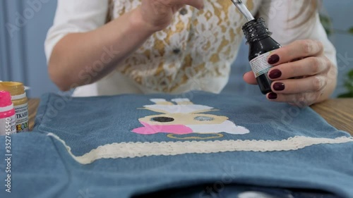 Designer painting on denim cloth. Making personal collection dresses for girls