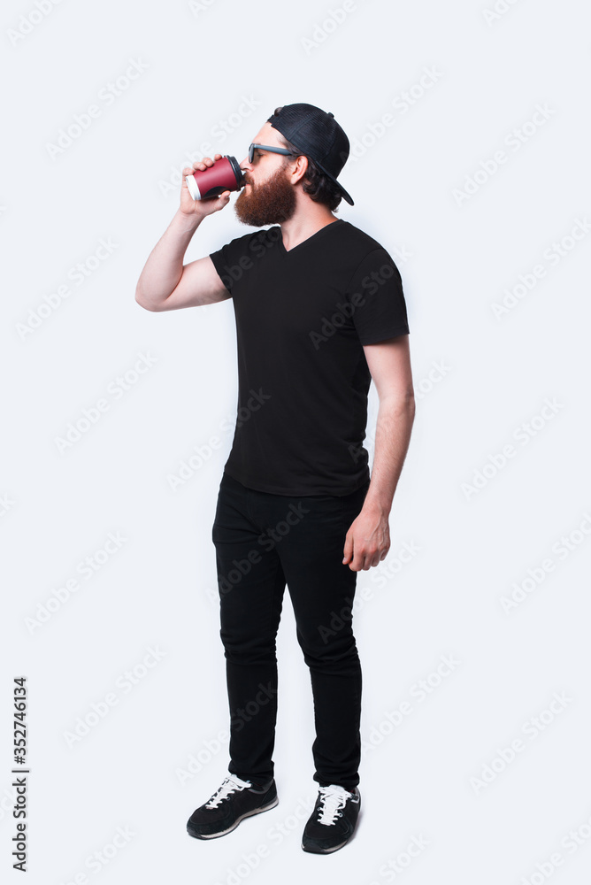 Full length photo of bearded man drinking cup of coffee Full length photo of bearded man drinking cup of coffee