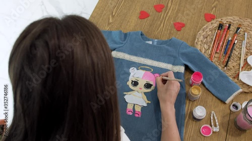 Designer painting on denim cloth. Making personal collection dresses for girls