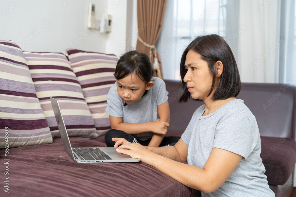 Asian mother and daughter using laptop studying homework online lesson at home, Social distance online education idea concept Asian mother and daughter using laptop studying homework online lesson at home, Social distance online education idea concept