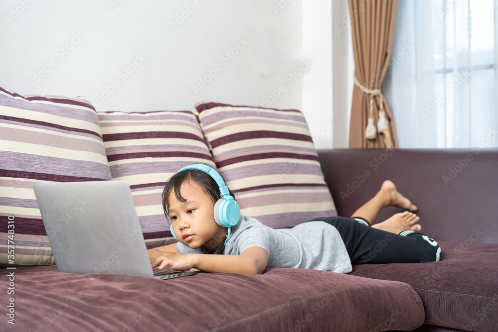 Asian little girl using laptop studying homework online lesson at home, Social distance online education idea concept Asian little girl using laptop studying homework online lesson at home, Social distance online education idea concept