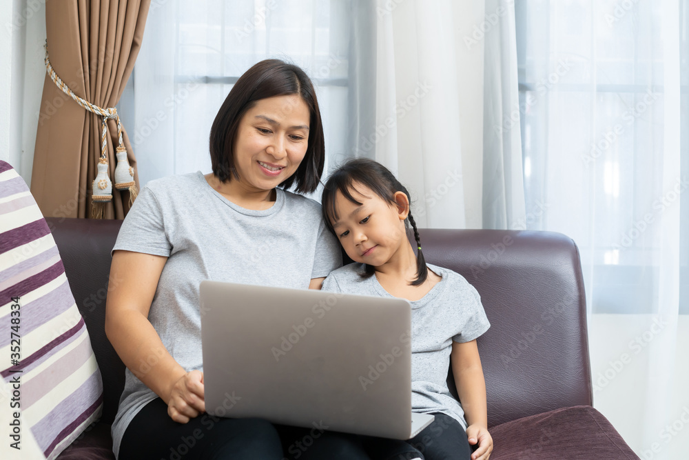Asian mother and daughter using laptop studying homework online lesson at home, Social distance online education idea concept Asian mother and daughter using laptop studying homework online lesson at home, Social distance online education idea concept