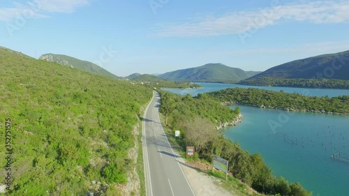 Aerial shot of empty road on mountain by sea against sky, drone is descending - Ston, Croatia photo